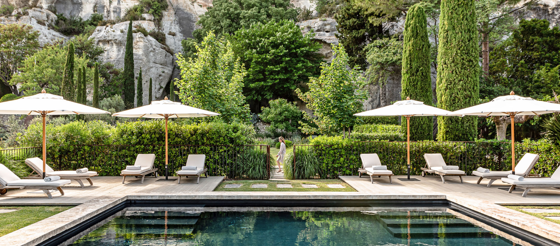 A serene oasis awaits, with a crystal-clear pool embraced by elegant lawn chairs and umbrellas.